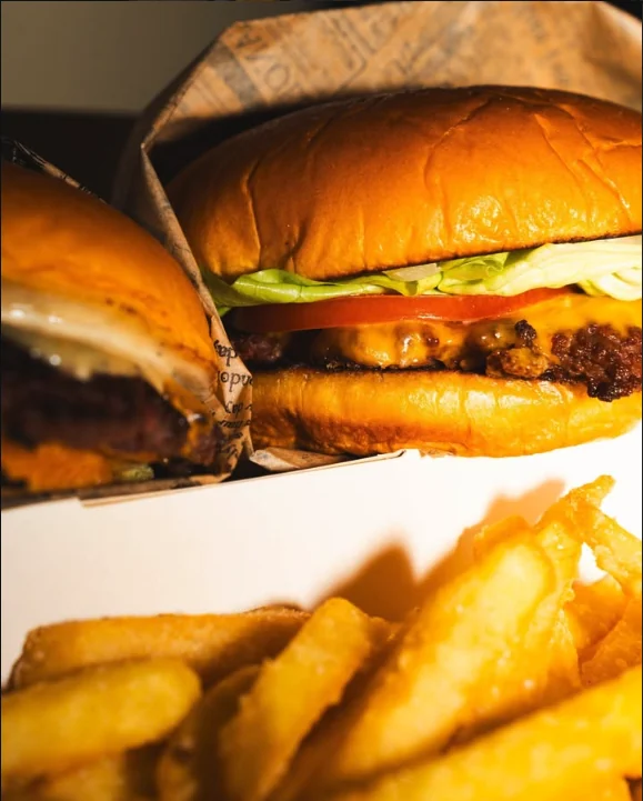 Classic burger con insalata e pomodoro, con le patatine in primo piano