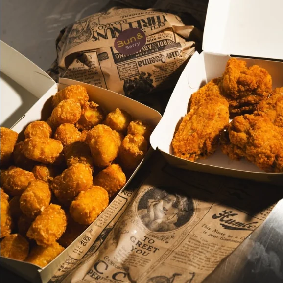 Potato pops e pollo fritto nelle scatole, sulla carta di giornale