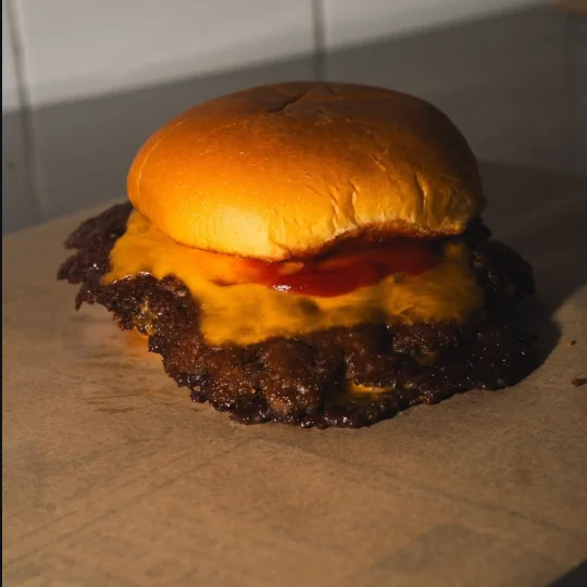 Smash cheeseburger con cheddar fuso e ketchup sulla carta da forno